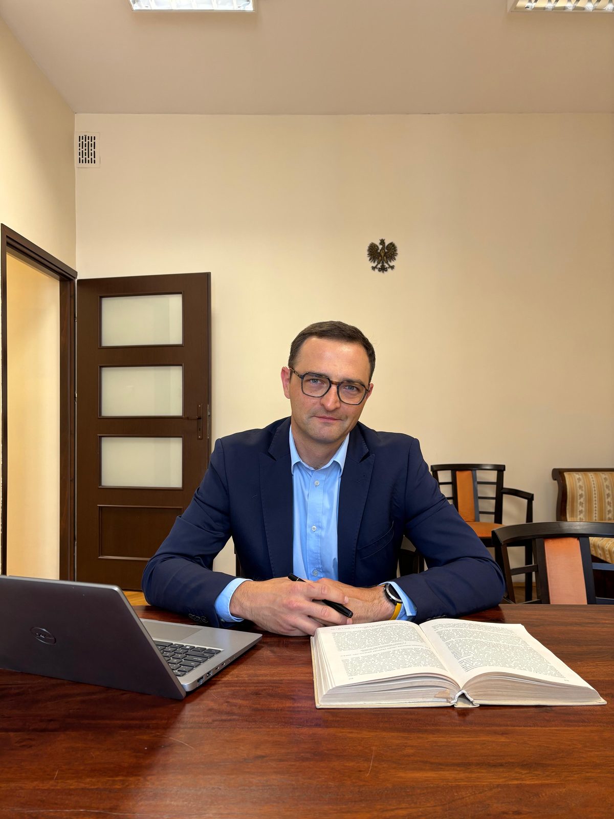 Notariusz Bartosz Krzysztofowicz przy biurku w swojej kancelarii w Tarnowie